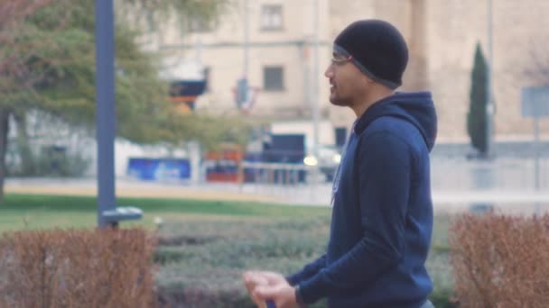 Pouliční cvičení výcvik. Mužské začátečník dělá koncentrace curl s kapelou odpor na venkovní posilovna v deštivé parku. — Stock video