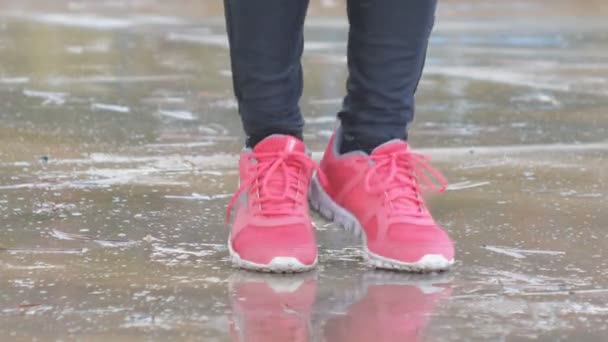 Primer plano de los pies femeninos en zapatillas de deporte rosa. Mujer saltando en una cuerda bajo la lluvia . — Vídeo de stock