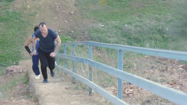 Entraînement avec entraîneur personnel à l'extérieur. Deux homme de fitness jogging monter les escaliers dans le cadre d'une routine d'entraînement . — Video