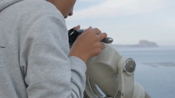 Gros plan d'un adolescent regardant la mer dans le télescope depuis le pont d'observation élevé . — Video