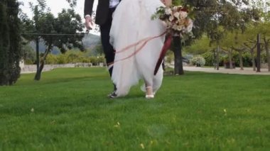 Gelin ve damat yeşil çimlerde yürüyor.