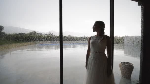 Schöne Braut am Fenster mit Regentropfen. — Stockvideo