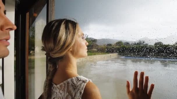 Preciosa pareja cerca de la ventana con gotas de lluvia . — Vídeo de stock