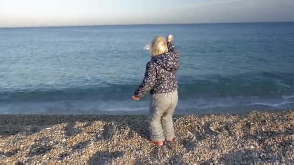 Klein meisje spelen op kiezelstrand. — Stockvideo