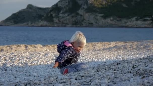 Klein meisje spelen op kiezelstrand. — Stockvideo