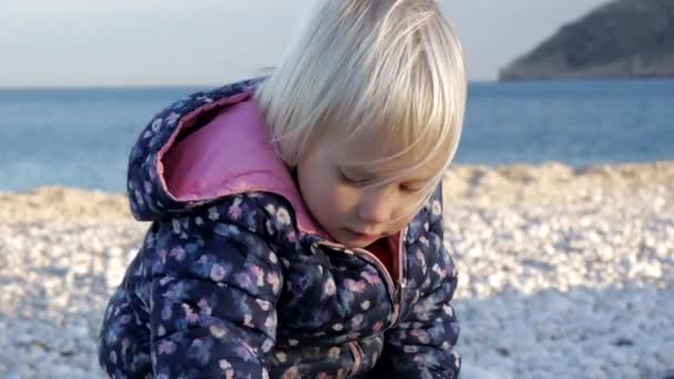 Çakıl taşlı plajda oynayan küçük kız. — Stok video