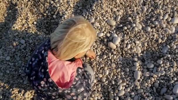 小女孩在鹅卵石沙滩上玩耍. — 图库视频影像