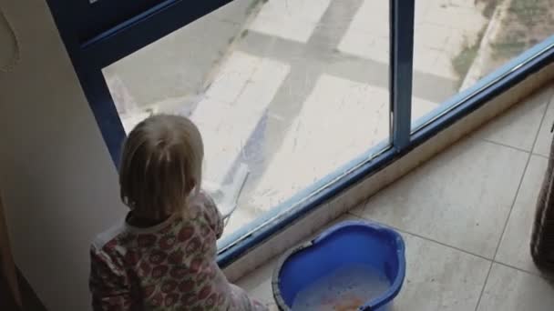 Kind spielt Fenster putzen. — Stockvideo