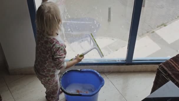 Kind spielt Fenster putzen. — Stockvideo