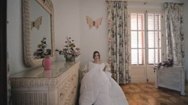 Beyaz battaniyeye sarılı genç bir kadın evinde oturuyor..