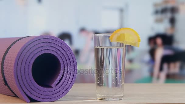 Entrenamiento de yoga, pilates, colchoneta de fitness, vaso con agua y limón — Vídeo de stock