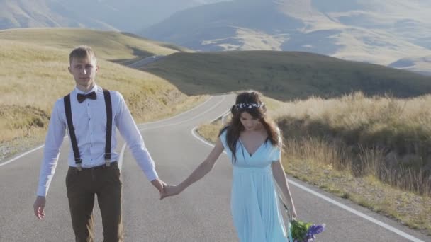 Stílusos pár megy a kéz az út a hegyek között — Stock videók