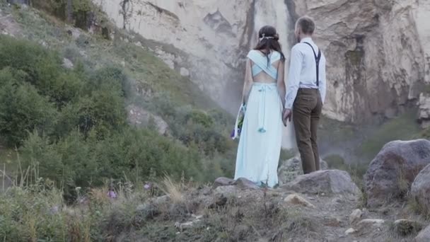 Elegante jovem casal posando contra um fundo cachoeira — Vídeo de Stock