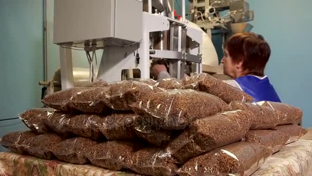 El trabajo de una mujer en una línea de embalaje con trigo sarraceno — Vídeo de stock