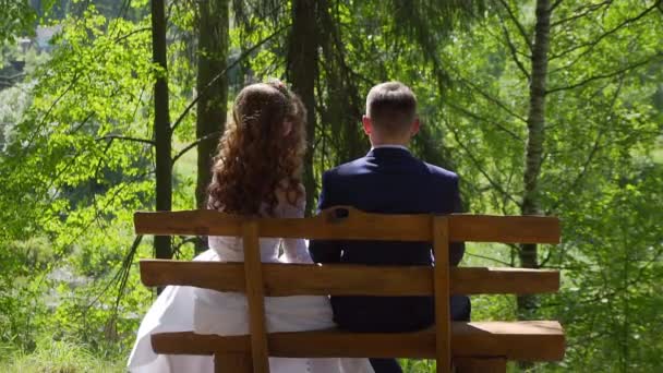 Bruden och brudgummen på bänken i parken — Stockvideo