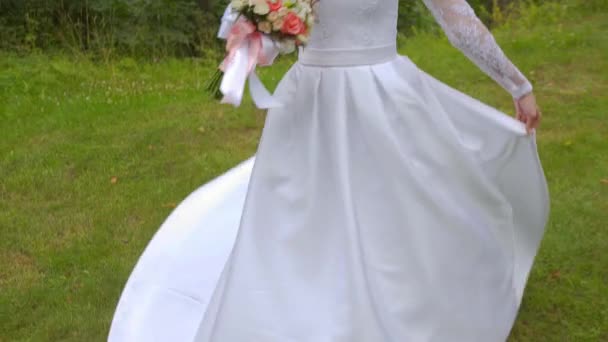 Девушка в платье невесты кружится и улыбается в камеру — стоковое видео