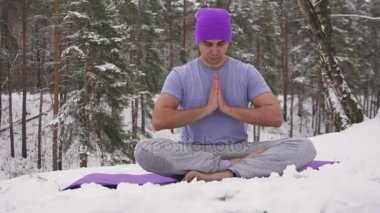 Kışın ormanda yoga yapan bir adam.