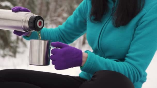 Chica en invierno en la naturaleza vierte té caliente de termos — Vídeo de stock