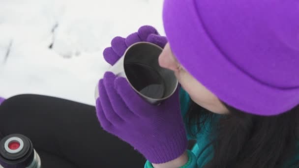 Девушка пьет горячий чай или кофе, на открытом воздухе зимой — стоковое видео