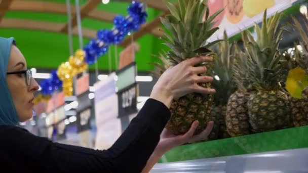 Muslimisches Mädchen kauft ein, wählt frische Ananas, Nahaufnahme — Stockvideo