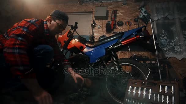 Mecânico masculino reparar uma motocicleta na garagem — Vídeo de Stock