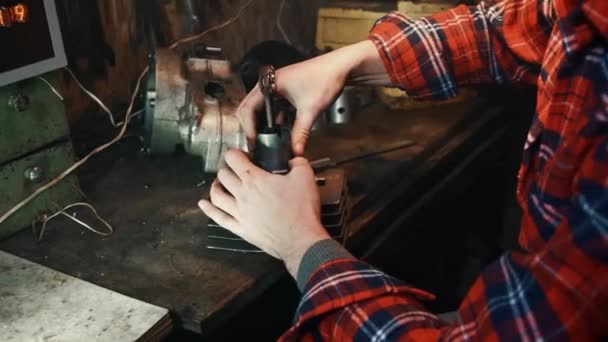 Человек мастер, собирает двигатель мотоцикла на столе в мастерской — стоковое видео