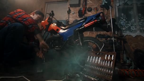 Mechanik mężczyzna naprawa silnika motocykl w garażu — Wideo stockowe