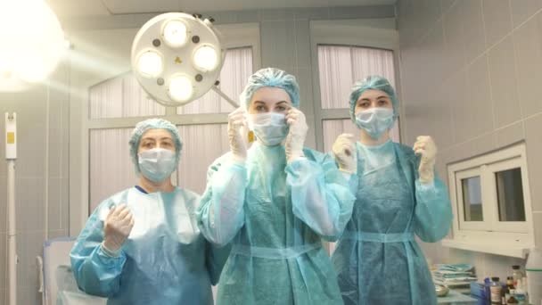 Tres niñas enfermera en el quirófano quitarse la mascarilla y sonreír — Vídeo de stock