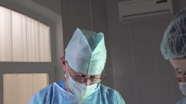 yakın çekim cerrahi bir operasyon sırasında kameraya bakar ve onaylayarak sallıyor