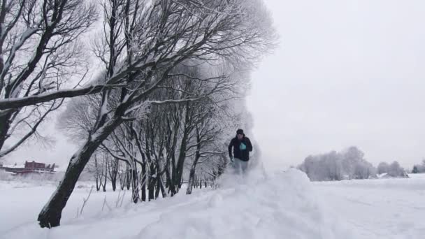 Mannen springer genom djup snö på vintern i parken — Stockvideo