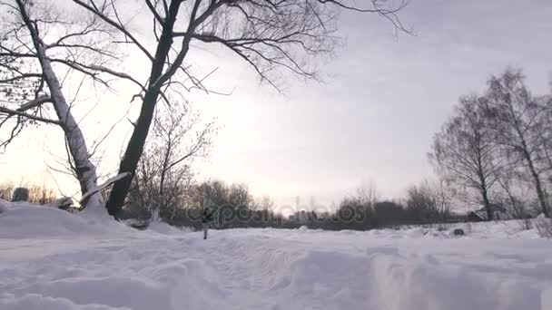 Een man in de schemering bij zonsondergang loopt door diepe sneeuw — Stockvideo