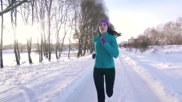 Девушка бегает по зимнему парку в солнечный день — стоковое видео