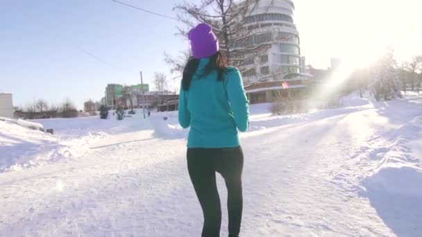 Брюнетка бег трусцой в солнечный зимний день на фоне городского пейзажа — стоковое видео