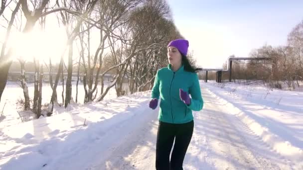 Menina corre através do parque de inverno em um dia ensolarado — Vídeo de Stock