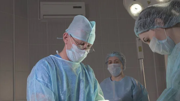 the surgeon shows, teaches two nurses in the operating room