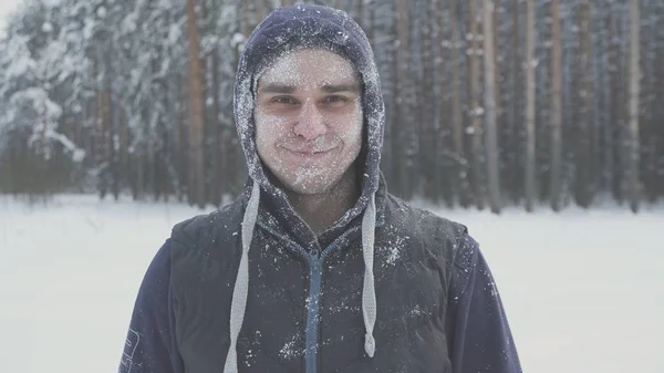 Улыбающийся замерзший человек в снегу смотрит в камеру в зимнем лесу после снежной бури иммунитет и холод — стоковое фото