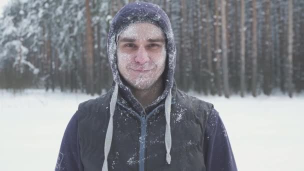 Замерзший мужчина снимает очки в зимнем лесу после снежной бури, покрытой снегом — стоковое видео