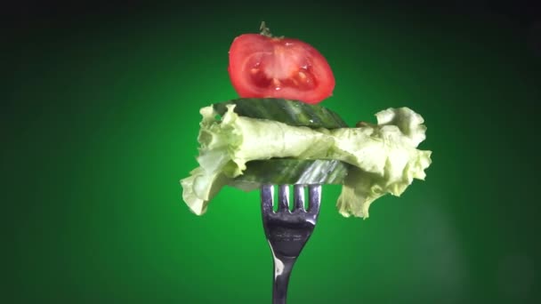 Vidlice s čerstvé červené řez rajčete a okurky v kapičky vody a salát otočí modré pozadí — Stock video