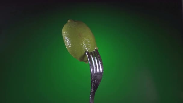 Gaffel med färsk lime med vatten droppar, rotation grön bakgrund — Stockvideo