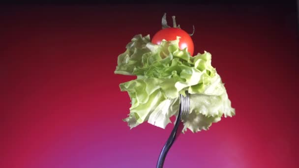 Garfo com tomate vermelho fresco e alface, rotação fundo vermelho — Vídeo de Stock