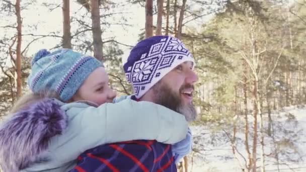 Una hijita montando a un padre barbudo paseando por el bosque y sonriendo — Vídeos de Stock