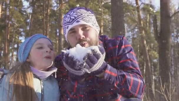 Meisje met haar vader waait sneeuw uit haar handen en glimlachen — Stockvideo