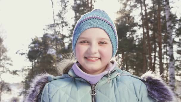 Портрет улыбающейся маленькой девочки в зимнем лесу — стоковое видео