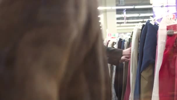 Mooi meisje in hijab pakt kleding in de winkel — Stockvideo