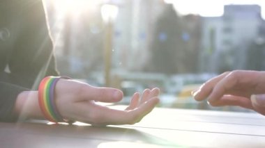 bir masanın arkasında Caddesi'nin arka planda Lgbt bilezik ile genç bir çift eller