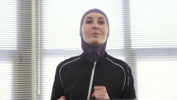 Female athlete in a hijab on a running simulator — Stock Video