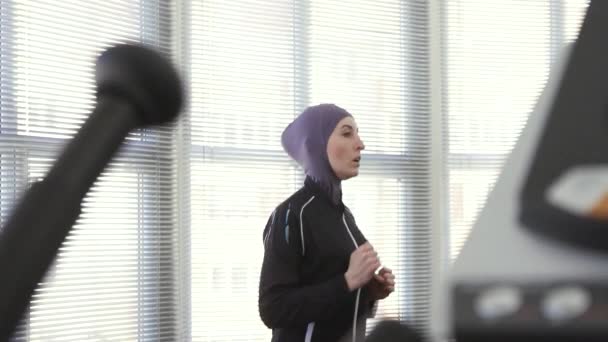 Atleta ragazza in hijab su un simulatore di corsa lento mo — Video Stock