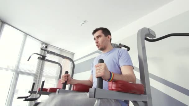 Ein schwuler Mann mit Armband in einem Fitnessstudio beschäftigt ist, eine aktive Position — Stockvideo