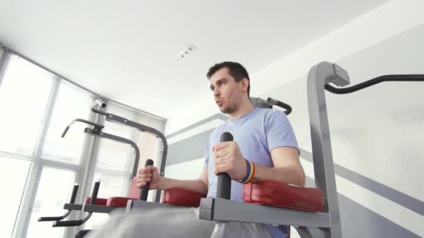 Un homme gay avec un bracelet est engagé dans une salle de gym, une position active — Video