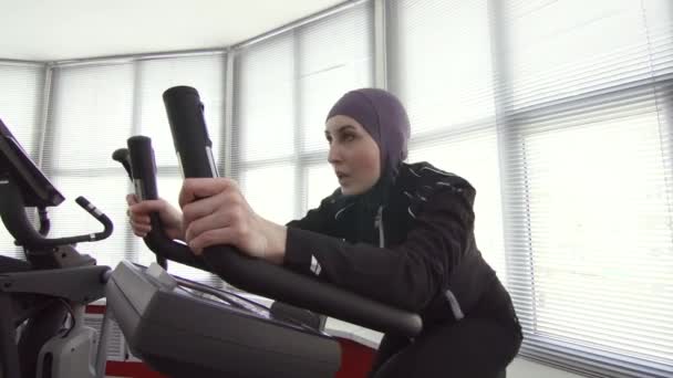 Жінка-спортсмен у спортивному хіджабі на симуляторі велосипеда — стокове відео